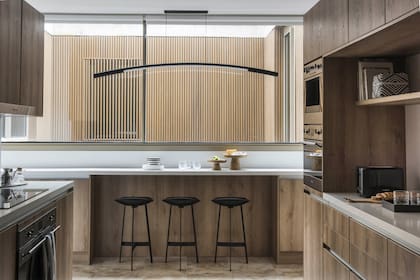 La cocina sigue la paleta y el estilo, donde sigue el mismo piso, la presencia de madera y cuero (en las banquetas de Sollos) y el diseño de autor en la gran lámpara colgante.