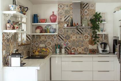 La cocina tiene mucha personalidad, con calcáreos en las paredes, muebles y estantes blancos.