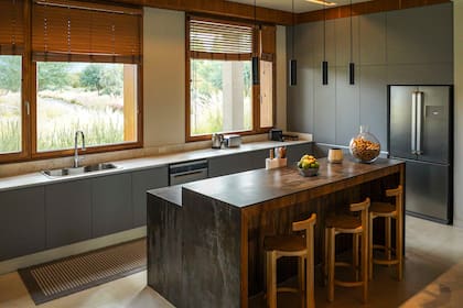 La cocina tiene una gran isla con banquetas (Quintana Casa) ideales para desayunar mirando al valle. Lamparas (Imdi). Cortinas (Riel Americano).