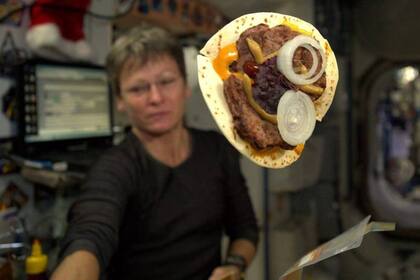 La comandante de la Expedición 51, Peggy Whitson, muestra la hamburguesa que preparó con una tortilla