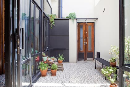La configuración típica del PH con galería les dio la idea de recrear un corredor con la flamante carpintería vidriada. Conservaron la puerta de entrada, restauraron la madera y cambiaron el vidrio marrón por uno traslúcido reforzado.