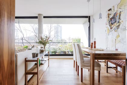 La consola de petiribí y mármol de Carrara (Lacroze Design Studio) garantiza la continuidad de los ambientes. Además de tapar la espalda del sillón, ahí es donde apoyan todo cuando llegan.