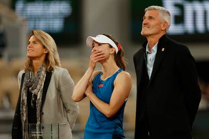 La director del Abierto de Francia y exjugadora Amelie Mauresmo y Gilles Moretton, presidente de la Federación de Tenis de Francia junto a la tenista francesa Alizé Cornet viendo el video de despedida después de que perdió en la primera ante la china Zheng Qinwen el martes 28 de mayo del 2024. (AP Foto/Jean-Francois Badias)