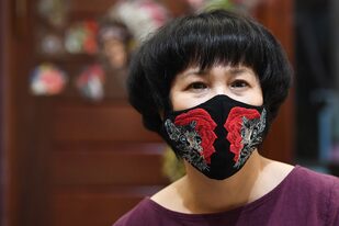 La diseñadora Do Quyen Hoa posa con su colorida mascarilla bordada a mano, utilizada como medida preventiva contra la propagación del nuevo coronavirus, en su taller en Hanoi, Vietnam, el 13 de abril de 2020