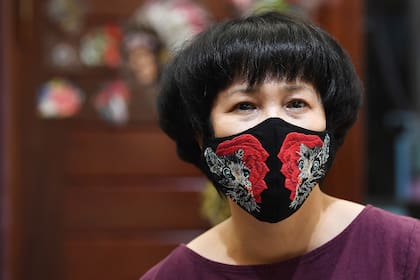 La diseñadora Do Quyen Hoa posa con su colorida mascarilla bordada a mano, utilizada como medida preventiva contra la propagación del nuevo coronavirus, en su taller en Hanoi, Vietnam, el 13 de abril de 2020