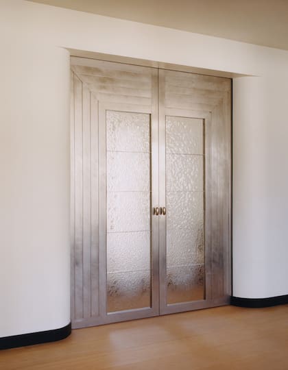La doble puerta al dormitorio, de aluminio y vidrio artesanal tiene claras reminiscencias art decó.