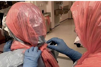 En medio del avance del coronavirus, la doctora Roberts ayuda a sus colegas a ponerse bolsas de basura en la cabeza.