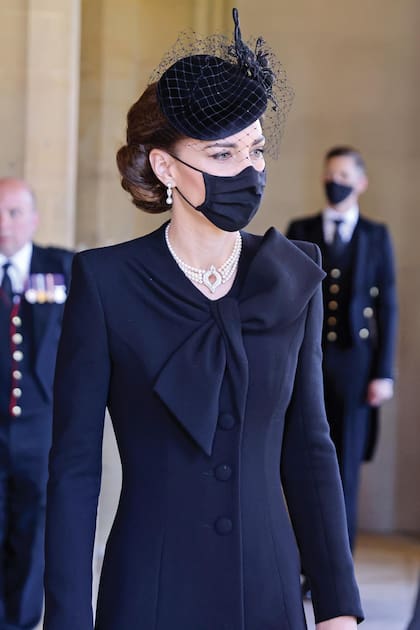 La duquesa de Cambridge
optó por un abrigo negro
de Catherine Walker
(firma favorita de Diana
de Gales) con cuerpo
entallado y bajo evasé,
decorado con una sobria
y elegante lazada en el
escote. Una pieza que
ya llevó en 2018 durante
el Royal British Legion
Festival of Remembrance.
El tocado con velo era de
Philip Treacy.