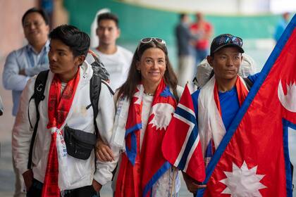 La escaladora noruega Kristin Harila (centro) y su sherpa Tenjen Sherpa (derecha), que el 3 de agosto establecieron un nuevo récord al subir las 14 cumbres más altas del mundo en 92 días, a su llegada al aeropuerto de Katmandú, Nepal, el 5 de agosto de 2023. (AP Foto/Niranjan Shreshta)