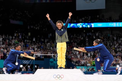 La estadounidense Jordan Chiles (derecha) y su compatriota Simone Biles celebran a la brasileña Rebecca Andrade, la vencedora en suelo; la foto puede quedar invalidada: el TAS falló en favor de la rumana Ana Barbosu por el tercer lugar y ahora debe decidir el COI.