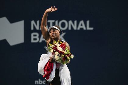 La estadounidense Serena Williams, deja la cancha con un ramo de flores y despidiéndose de los aficionados tras caer ante la suiza Belinda Bencic, el miércoles 10 de agosto de 2022, en el Masters de Toronto. (Nathan Denette/The Canadian Press via AP)