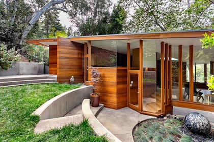 La estructura de madera domina la entrada, integrándose con el diseño orgánico de la vivienda