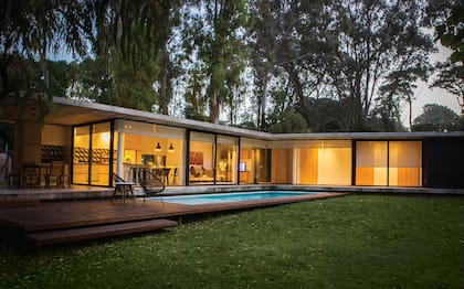 La fachada de la casa es mucho más cerrada que el contrafrente, que da a la pileta. Todos los ambientes tienen vista abierta hacia ese espejo de agua y a los árboles del bosque.