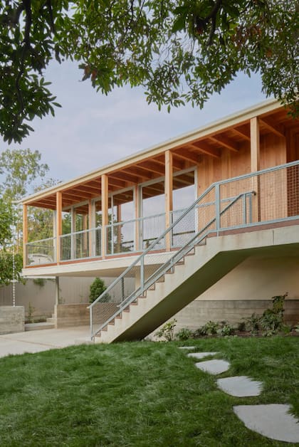 La fachada principal de la casa presenta un balcón continuo con barandas de madera y metal.