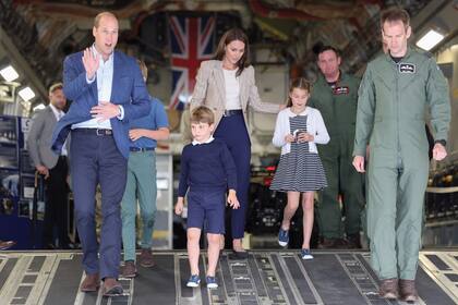 La familia real desciende de la aeronave C-17. Kate llevó un blazer de Blazé que acompañó con pantalones y con chatitas de Emmy London. Su hija Charlotte lució un cárdigan de Reiss, vestido a rayas de Rachel Riley y zapatillas Trotters.