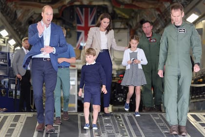 La familia real desciende de la aeronave C-17. Kate llevó un blazer de Blazé que acompañó con pantalones y con chatitas de Emmy London. Su hija Charlotte lució un cárdigan de Reiss, vestido a rayas de Rachel Riley y zapatillas Trotters.