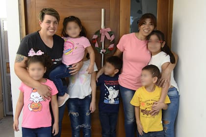La familia sonríe frente a la puerta de su casa.