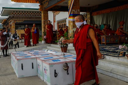 La foto distribuida por UNICEF muestra a monjes del organismo monástico de Paro realizar un rito cuando 500.000 dosis de la vacuna de Moderna contra el COVID-19 llegan desde Estados Unidos al Aeropuerto Internacional de Paro, Bhutan, 12 de julio de 2021.  (UNICEF via AP)