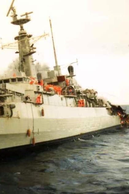 La fragata HMS Ardent en llamas, en sus últimas horas. Su tripulación, con trajes antiflama naranjas, se prepara para el abandono