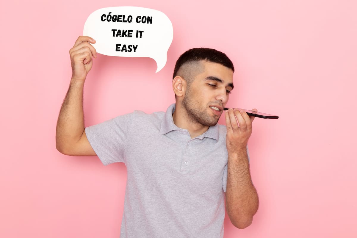 La frase combina dos sentidos: “cógelo” sugiere una actitud frente a algo y “take it easy” apunta a tomárselo con calma