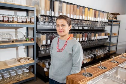 La fundadora y propietaria de Precycle, Katerina Bogatireva, frente a una fila de “chimeneas” que contienen los productos en su tienda de comestibles con cero residuos y sin embalaje en Nueva York
