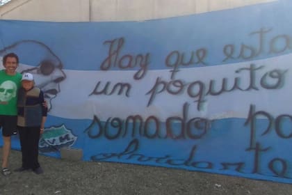 La Fundamentabuela Lidia y su hijo Dante junto a una bandera con un verso de la canción "Martinis y tafiroles"