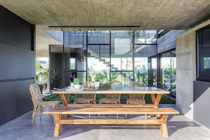 La galería con parrilla se abre al patio central y al jardín posterior. Se equipó con una gran mesa, banco de madera y sillas de caña (Negro).
