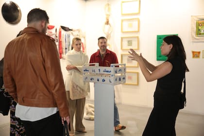 La galerista Pamela González explica la obra de Agustina Lazarte, un cajón de limones pintado al estilo porcelana holandesa con escenas del mercado central tucumano
