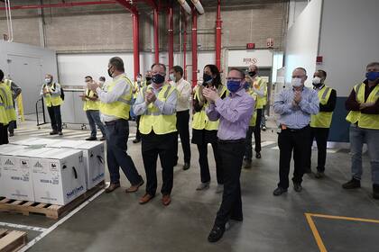 La gente aplaude cuando las cajas que contienen la vacuna de Pfizer y BioNTech contra el coronavirus se preparan para ser enviadas en la planta de fabricación de Pfizer Global Supply Kalamazoo el 13 de diciembre de 2020 en Portage, Michigan
