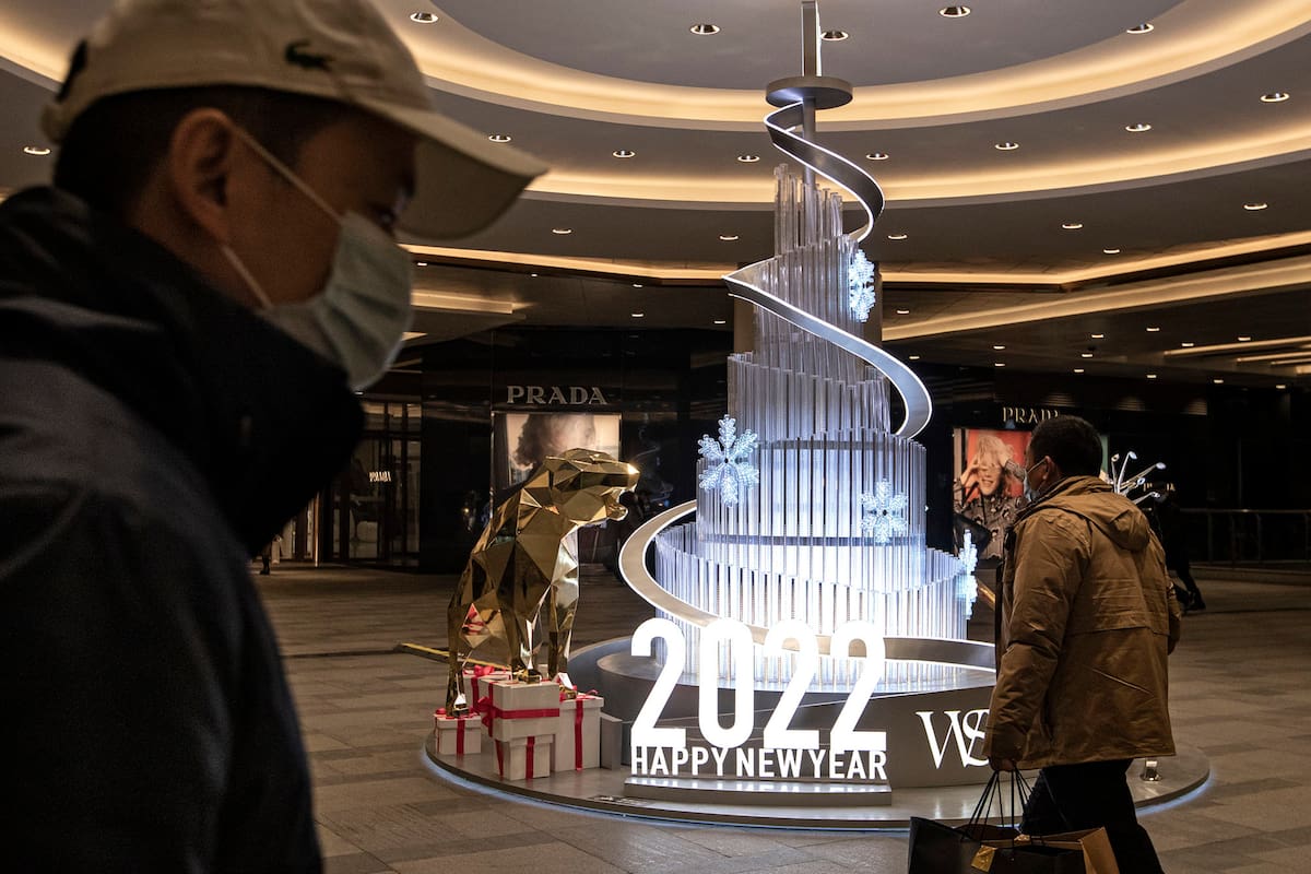 La gente camina frente al logotipo de 2022 en la plaza internacional de Wuhan el 31 de diciembre de 2021 en Wuhan, China.