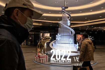 La gente camina frente al logotipo de 2022 en la plaza internacional de Wuhan el 31 de diciembre de 2021 en Wuhan, China.