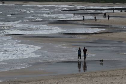 La gente camina por la playa en Atlántida, departamento de Canelones, Uruguay, el 15 de noviembre de 2020, en medio de la pandemia de coronavirus