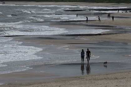 La gente camina por la playa en Atlántida, departamento de Canelones, Uruguay, el 15 de noviembre de 2020, en medio de la pandemia de coronavirus