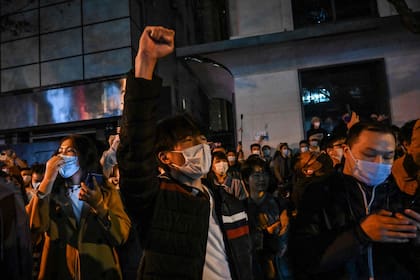 La gente canta eslóganes mientras se reúne en una calle de Shangai el 27 de noviembre de 2022, donde la noche anterior se produjeron protestas contra la política china de cero celo tras un incendio mortal en Urumqi, la capital de la región de Xinjiang.