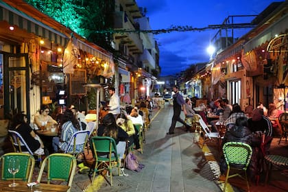 La gente come en un restaurante en la ciudad costera israelí de Tel Aviv el 7 de marzo de 2021, después de que las autoridades reabrieran restaurantes, bares y cafés a los titulares de "pases verdes" vacunados