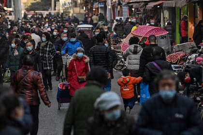 La gente con barbijo camina por una calle cerca de un mercado en Wuhan, provincia central de Hubei en China, el 19 de enero de 2021