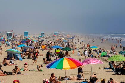 La gente disfruta de la playa en medio de la nueva pandemia de coronavirus en Huntington Beach, California, el 25 de abril de 2020. - El Condado de Orange es el único condado en el área donde las playas permanecen abiertas, los socorristas en Huntington Beach esperan que decenas de miles de personas