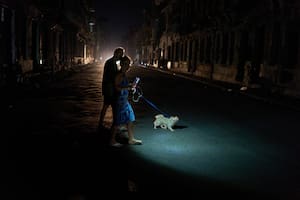 La gente enciende una linterna mientras cruza una calle con su perro durante un apagón en La Habana