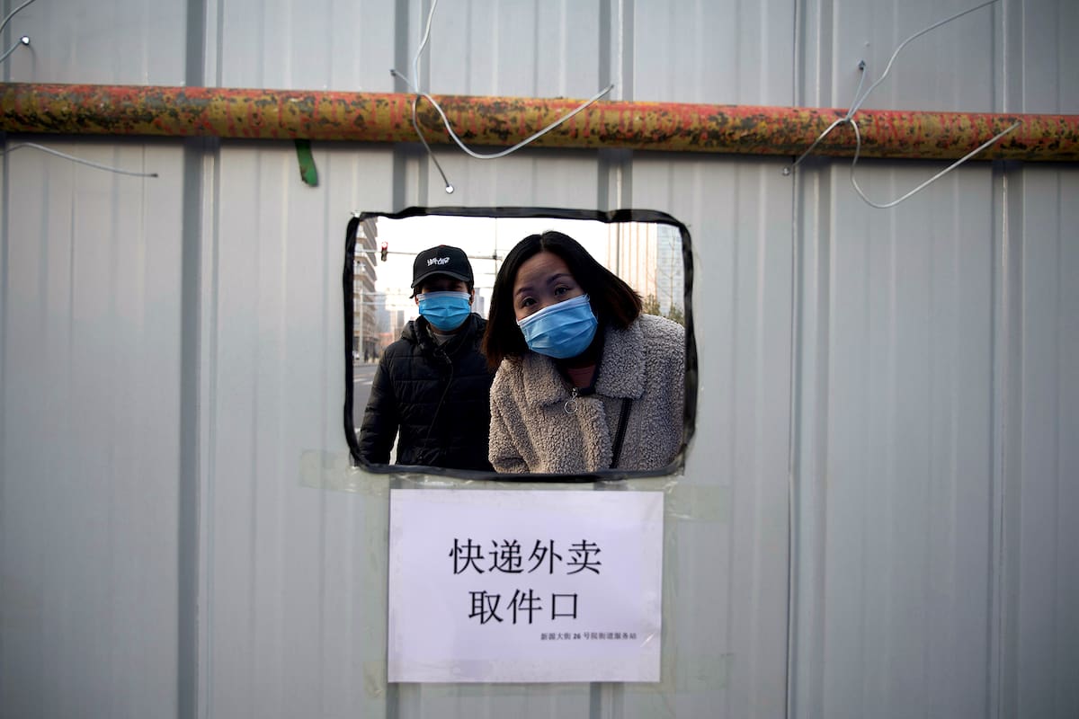 La gente espera su pedido dentro de un área con barricadas en el distrito Daxing de Pekín el 21 de enero de 2021, después de que se impusiera un cierre parcial en la capital china por el avance del coronavirus