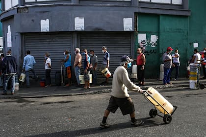 La gente forma fila para conseguir agua en las calles de Caracas; la pobreza y el trabajo informal son el mayor problema para cumplir la cuarentena en Venezuela