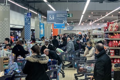 La gente hace cola con su carrito de compras completamente lleno de productos en un supermercado, en Villiers-sur-Marne, en las afueras de París