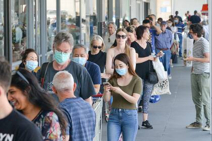 La gente hace cola en un supermercado después de que el gobierno del estado de Australia del Sur anunció un cierre de seis días debido a un brote de coronavirus Covid-19 en Adelaida el 18 de noviembre de 2020