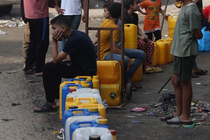 La gente hace cola para recibir agua después de los ataques israelíes en la ciudad de Gaza el 28 de octubre de 2023