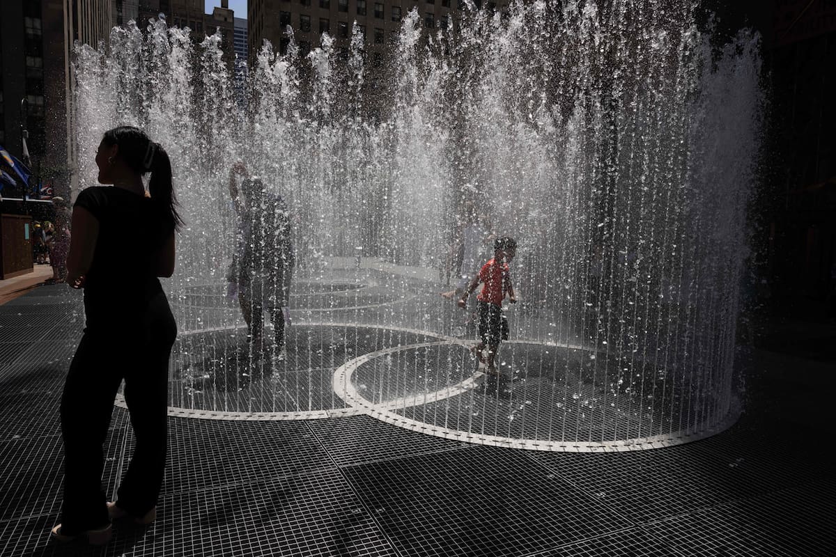 La gente juega en la escultura acuática del artista Jeppe Hein titulada "Changing Spaces" en el Rockefeller Center Plaza de Nueva York el 19 de julio de 2022, mientras continúa la ola de calor en Europa y Norteamérica.