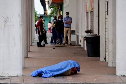 La gente mira a un hombre que colapsó en la vereda en Guayaquil