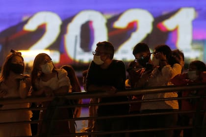 La gente observa después de la cuenta regresiva para el Año Nuevo, ya que los tradicionales fuegos artificiales de Nochevieja se cancelan debido al brote de la enfermedad por coronavirus (COVID-19), en Marina Bay en Singapur