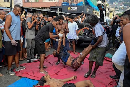 La gente se concentró alrededor de los muertos en la plaza en Río de Janeiro
(Photo by Pablo PORCIUNCULA / AFP)