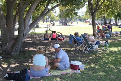 La gente se refugió bajo la sombra de los árboles que bordeaban la costa de Quilmes