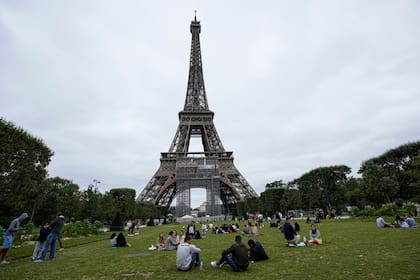 La gente se relaja en el jardín Champ-de-Mars junto a la Torre Eiffel en París
