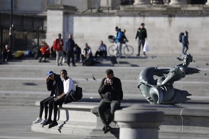 La gente se relaja en Trafalgar Square en Londres el 25 de marzo de 2020, después de que el gobierno de Gran Bretaña ordenó un cierre para frenar la propagación del nuevo coronavirus